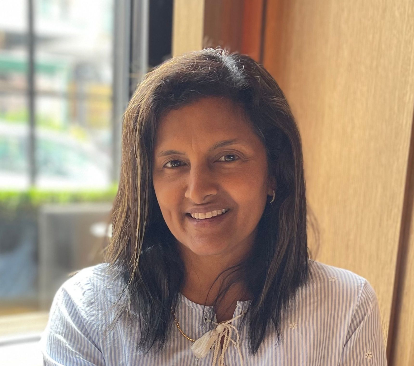 Portrait of Dr. Yadalla beside a window, sunlight highlighting her warm, welcoming smile.
